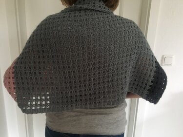 Rückansicht eines gehäkelten Netztuchs mit grauem Mittelteil und farbigen Enden