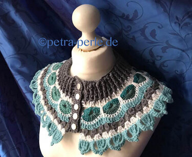 Gehäkelter Kragenschal mit Muschel- und Wellenmuster in Türkis, Grau und Weiß, vorne geknöpft auf einer Schneiderpuppe