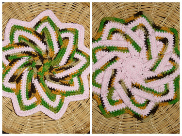 Sternförmiger, gehäkelter Topflappen mit Spiralmuster in Rosa, Grün, Braun und Gelb auf Korbuntergrund