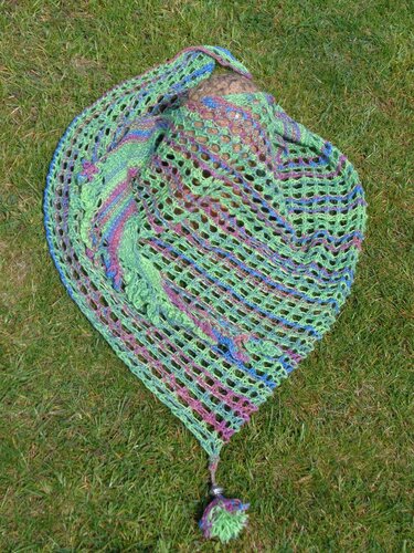 Gestricktes Dreieckstuch in grün, blau und lila mit offenem Lacemuster und Bommel auf Gras