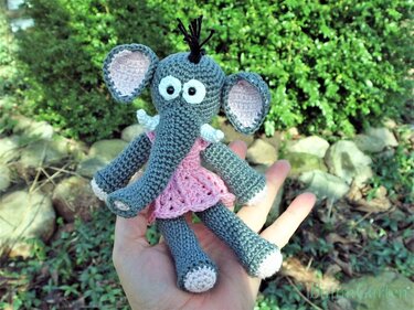 Gehäkelte graue Elefanten-Fingerpuppe mit rosa Kleid in einer Hand