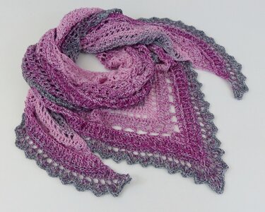 Gehäkeltes Dreieckstuch in Rosa, Lila und Grau mit Muschelrand und offenem Häkelmuster.
