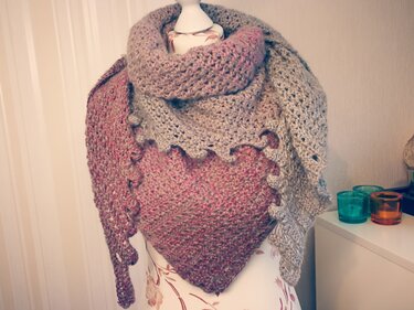 Gehäkeltes zweifarbiges Dreieckstuch in Rosa und Grau auf Schneiderpuppe mit wellenförmiger Kante.