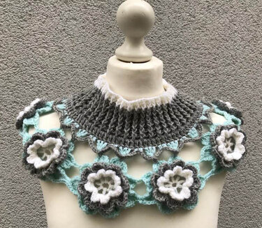 Mannequin mit gehäkeltem Kragenschal: grauer Rippenkragen, mintfarbenes Ajournetz und weiße sowie graue Blüten