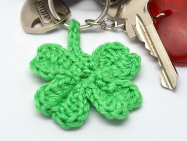 Gehäkeltes grünes vierblättriges Kleeblatt als Anhänger an einem Schlüsselring