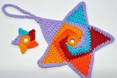 Handgehäkelter Stern mit bunten Spiralmustern und kleines vierblättriges Häkelmotiv