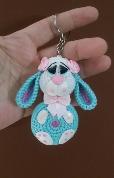 Gehäkelter Amigurumi-Hase als Schlüsselanhänger in Hellblau, Weiß und Rosa, an einem Schlüsselring gehalten.