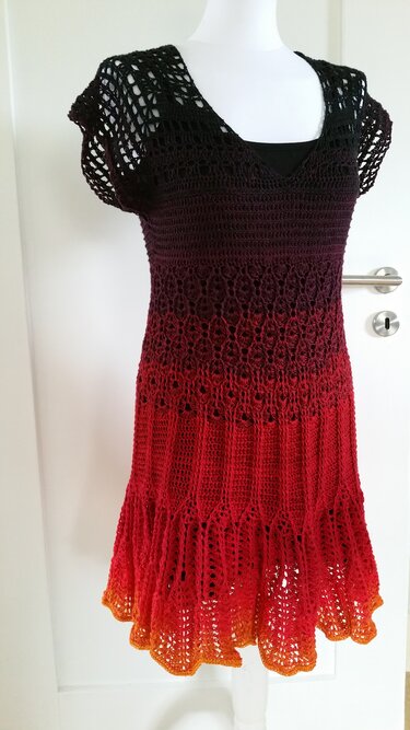 Mannequin trägt gehäkeltes Damenkleid mit Ombre‑Farbverlauf in Schwarz, Rot und Orange