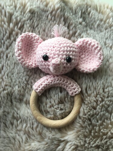 Rosa gehäkelter Elefanten-Beißring mit Holzring auf flauschigem Untergrund