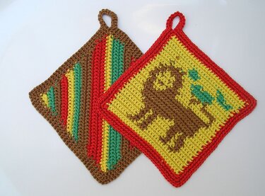 Zweier-Set gehäkelter quadratischer Topflappen, einer gelb mit braunem Elefantenmotiv und rotem Rand, einer gestreift, beide mit Aufhängeschlaufen