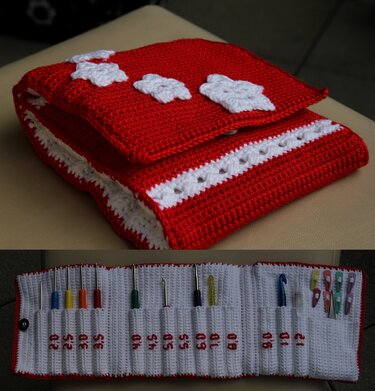 Rotes und weißes gehäkeltes Etui, geöffnet mit nummerierten Fächern und Häkelnadeln, verschließbar mit Druckknopf.