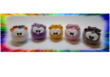 Nahaufnahme: fünf kleine gehäkelte Kugel-Amigurumi in mehreren Farben mit Augenapplikationen