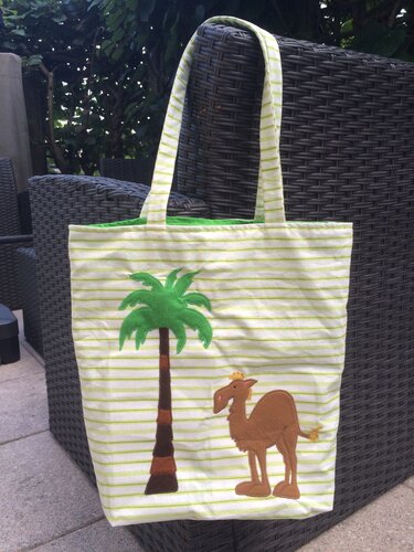Hellgrün-weiß gestreifte Stofftasche mit aufgenähter grüner Palme und braunem Kamel mit kleiner Krone.