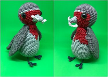 Gehäkelter Amigurumi-Vogel mit roter Brust und gehäkeltem Wurm vor grünem Hintergrund.