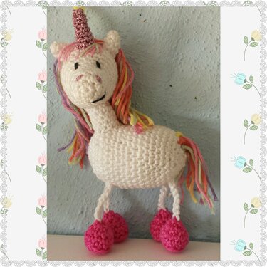 Gehäkeltes weißes Einhorn-Amigurumi mit rosa Horn, bunter Mähne und pinken Hufen