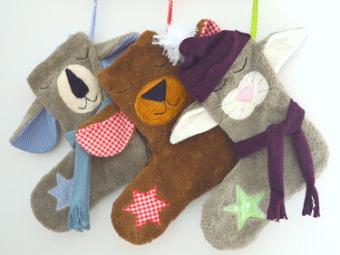 Drei tierförmige Weihnachtsstrümpfe aus flauschigem Stoff mit applizierten Sternen, Mützen und Aufhängeschlaufen