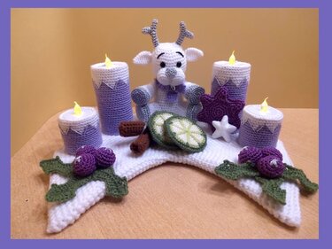 Gehäkelte Adventsdekoration mit Rentierfigur, vier lilafarbenen Kerzen mit Lichteffekt, Sternen, Beeren und grün-weißen Scheiben auf hellem Untergrund.