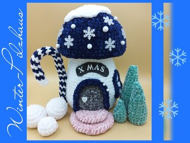 Nahaufnahme eines gehäkelten Amigurumi-Pilzhauses mit Schneeflockenapplikationen, gestreifter Zuckerstange und zwei gehäkelten Tannen
