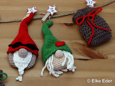 Two crocheted gnomes and a brown drawstring bag hung on twine with star number tags.