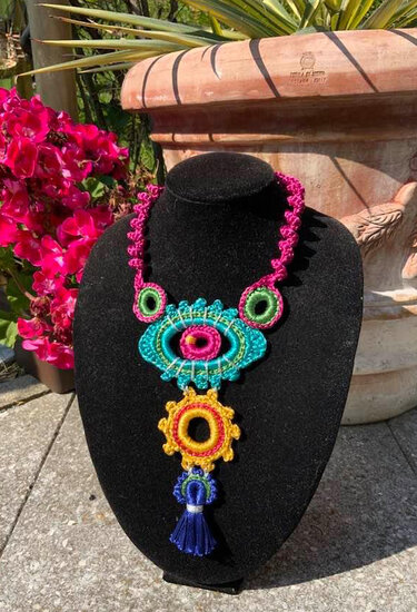 Bunte gehäkelte Halskette mit Quaste auf schwarzem Büsten