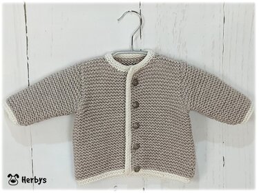 Handgestrickte Babyjacke in Beige mit cremeweißer Einfassung auf Kleiderbügel