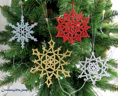 Four crocheted snowflake ornaments in silver, red, gold, and white hanging on a Christmas tree.