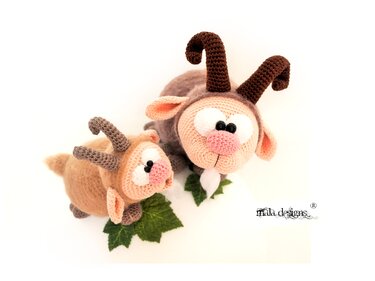Zwei gehäkelte Amigurumi-Ziegen, groß und klein, mit gebogenen Hörnern und rosa Nasen