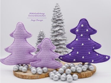 Drei gehäkelte Tannenbäume in Flieder und Violett, auf Holzscheiben mit silbernen Kugeln.