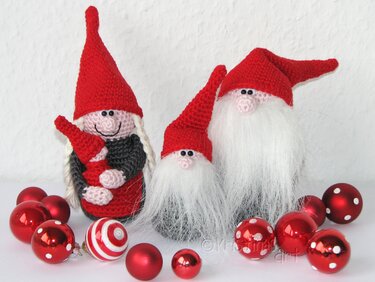 Drei gehäkelte Wichtel mit roten Mützen und roten Weihnachtskugeln