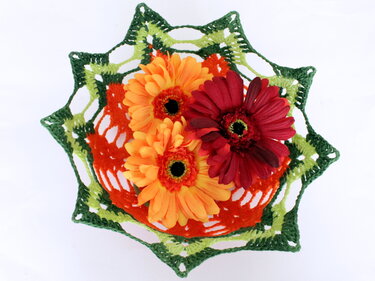 Von oben: sternf
rmiger, handgeh
kelter Korb in Orange und zwei Gr
nt
en, gef
llt mit drei Gerbera-Blumen