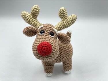 Handmade crocheted reindeer with red nose and brown body.