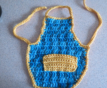 Handgehäkelte kleine Schürze, blau mit gelbem Rand und aufgesetzter Tasche