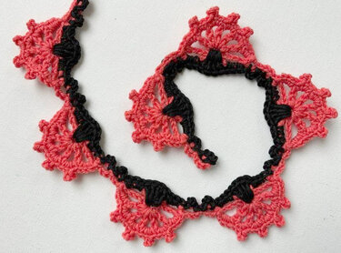 Korallfarbene Häkelborte mit dreieckigen Muschelmotiven und schwarzer Kettchenkante