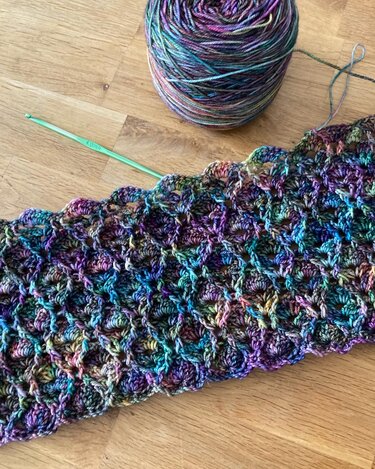 Gehäkeltes Stück mit Muschelmuster, Verlaufsgarn und 4,0 mm Häkelnadel auf Holz