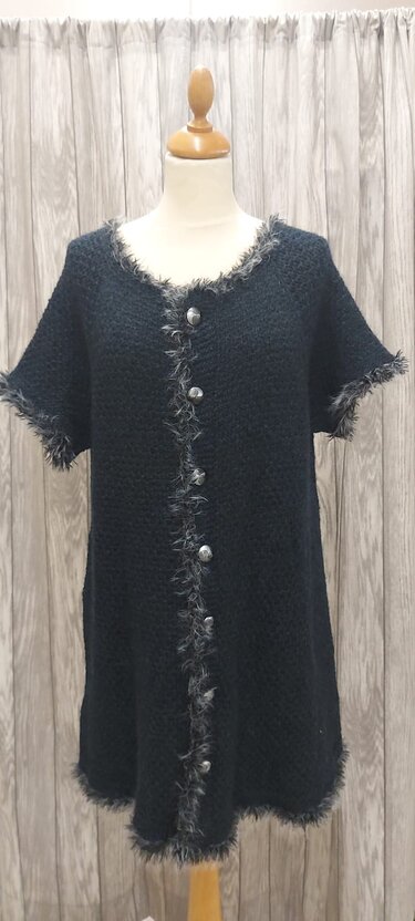 Lange schwarze Strickjacke mit Knopfleiste und flauschigem Fransenbesatz auf Schaufensterpuppe