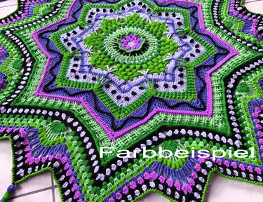Gehäkelte sternförmige Decke mit grün-lila-schwarzen Mandala-Mustern.