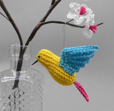 Mini Amigurumi Kolibri gehäkelt gelb blau rosa hängend an Draht