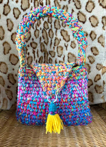 Bunte gehäkelte Tasche mit Umschlag, Ring und gelber Quaste