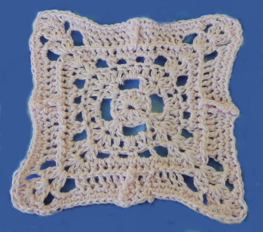Zartrosa gehäkeltes Quadrat mit offenem Muster auf blauem Hintergrund.