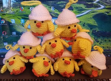 Handgehäkelte gelbe Amigurumi-Küken mit weißen Eierschalenmützen