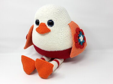 Gehäkelter Amigurumi-Vogel mit gestreiften Beinen und Blumenflügel