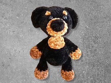 Schwarz-brauner gehäkelter Amigurumi-Hund mit großen Augen