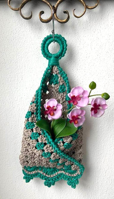 Gehäkelter hängender Utensilo in Beige und Türkis an einem Haken mit Orchideen als Dekoration
