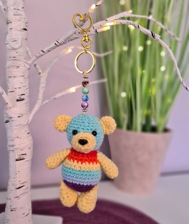 Gehäkelter Amigurumi-Teddy Schlüsselanhänger mit regenbogenfarbenem Körper und goldfarbenem Karabiner