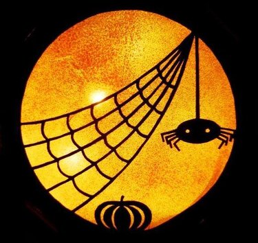 Runde einfarbige Silhouette mit Spinnennetz, hängender Spinne und Kürbis