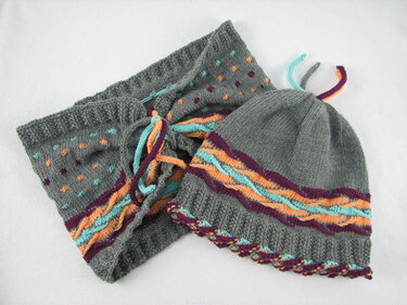 Grau gestricktes Mützen- und Loop-Set mit bunten Tupfen und gewellten Streifen