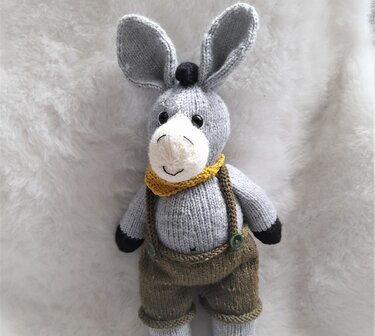 Gestrickter Amigurumi-Esel mit Trägerhose, gelbem Halstuch und schwarzen Pfoten