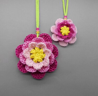 Two layered pink crochet flowers with yellow centers and bead-adorned neon cords, suitable for Mother's Day decor