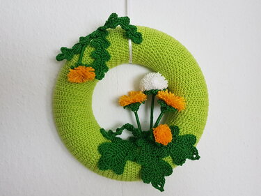 Gehäkelter grüner Türkranz mit gelben Löwenzahnblüten, weißer Pusteblume und grünen Blättern
