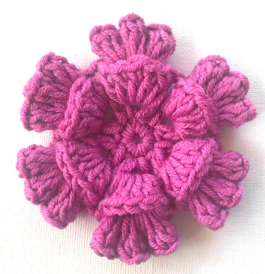 Gehäkeltes Blütenmotiv in Pink auf hellem Untergrund